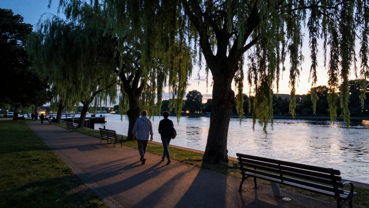 Two figures walking peacefully along the Thames at Brentford Lock at sunset.