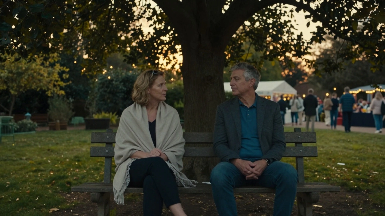 Two people sit quietly on a bench in Ealing Common at dusk, talking softly under a tree.