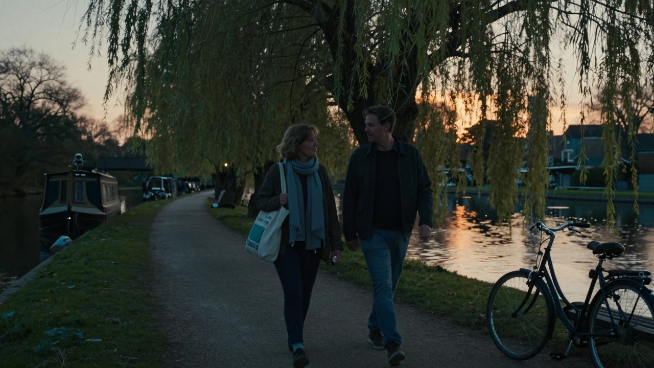 Two people walking peacefully along the Grand Union Canal at sunset, surrounded by trees and water.