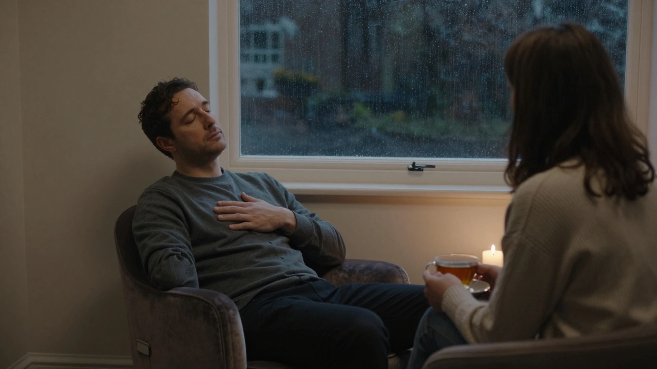 A man and woman sit in quiet companionship in a softly lit lounge, rain on the window behind them.