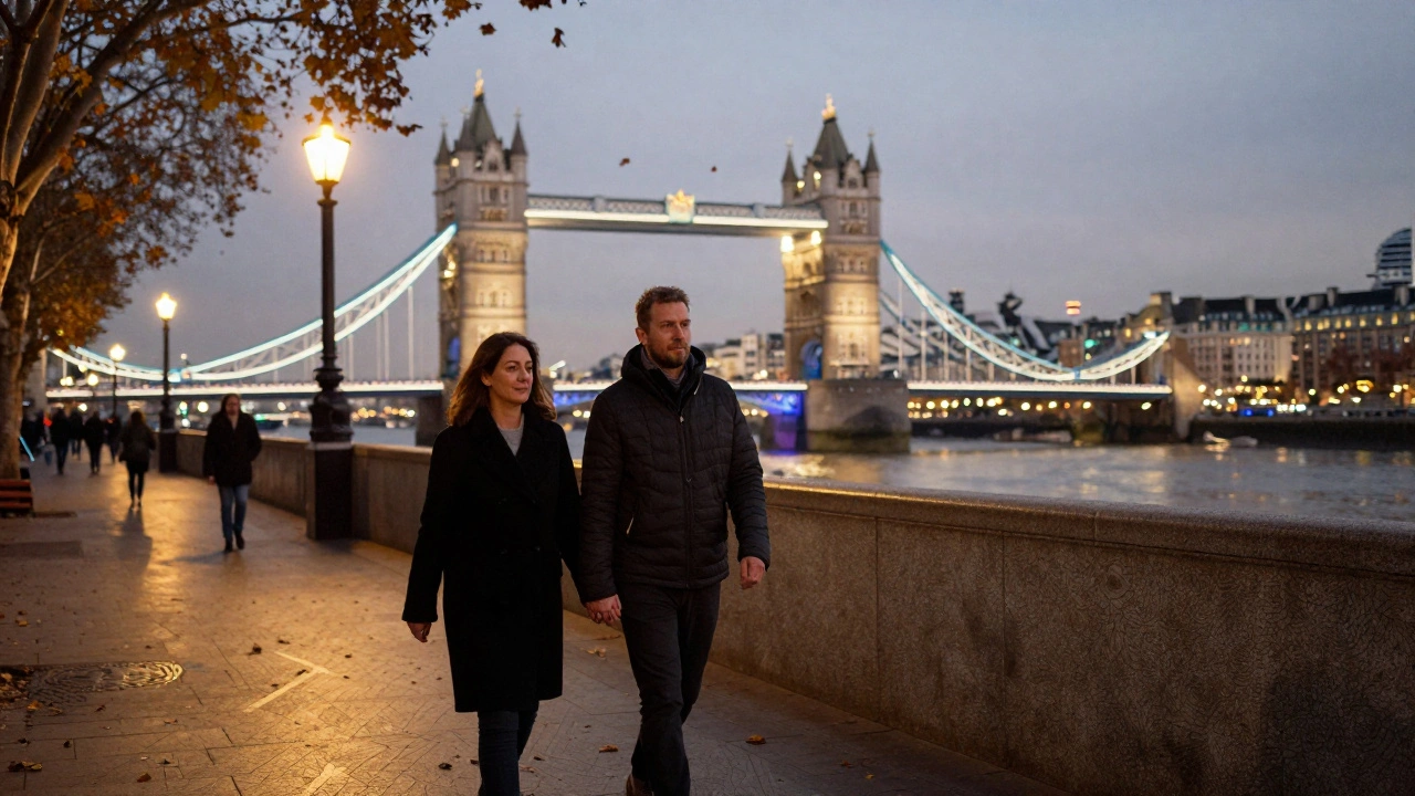 A man and woman walking hand in hand along the Thames at dusk, surrounded by London’s iconic skyline.