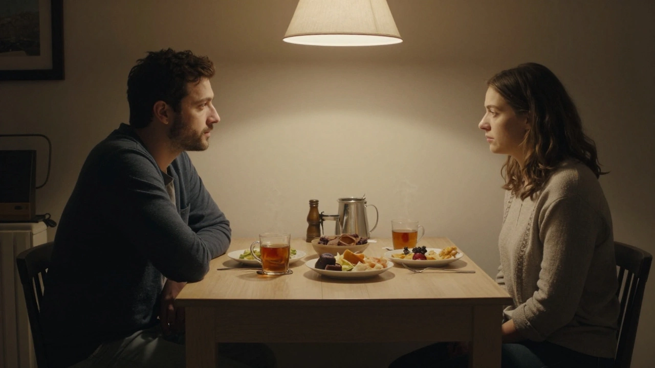 Two people share a quiet evening at a simple dining table, talking over tea and food.